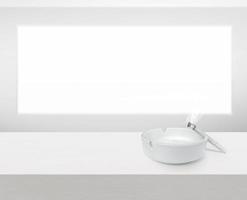 White ashtray and cigarette on white wooden table with copy space photo