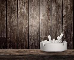 Ashtray full of cigarettes butts on wooden table photo