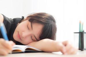 hermoso retrato joven mujer asiática sonrisa y feliz escritura aprendizaje examen o tarea y acostado con escritorio, estilo de vida belleza asia chica con trabajo, educación y concepto de negocios. foto