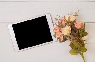 Happy mother day or valentine day with tablet display blank and flower on wooden table pastel tone, feeling romantic with decoration, present festive with on desk, top view, holiday concept. photo