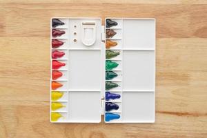 Watercolor paints set. Color in watercolor palette with wooden background. photo