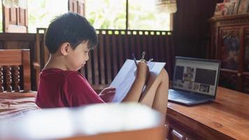 los niños asiáticos disfrutan del tiempo libre practicando el dibujo a lápiz en casa durante las vacaciones escolares. concepto de creadores de niños foto