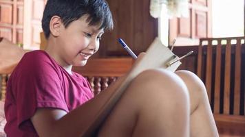 Asian boys enjoy free time practicing pencil drawing at home during school holidays. Kid Creators concept photo