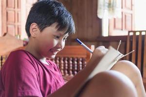 los niños asiáticos disfrutan del tiempo libre practicando el dibujo a lápiz en casa durante las vacaciones escolares. concepto de creadores de niños foto