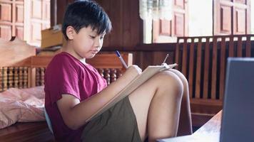 los niños asiáticos disfrutan del tiempo libre practicando el dibujo a lápiz en casa durante las vacaciones escolares. concepto de creadores de niños foto