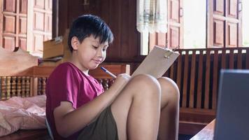 los niños asiáticos disfrutan del tiempo libre practicando el dibujo a lápiz en casa durante las vacaciones escolares. concepto de creadores de niños foto