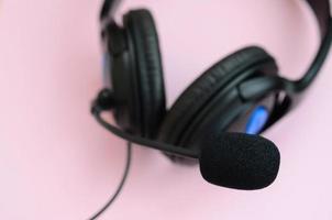 Music listening concept. Black headphones lies on pink background photo