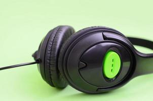 Music listening concept. Black headphones lies on green background photo