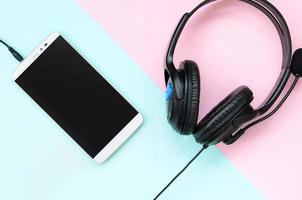 Black headphones and smartphone lies on a colorful pastel violet background photo