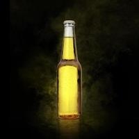 Beer bottle with water drops on the yellow color smoke black background photo