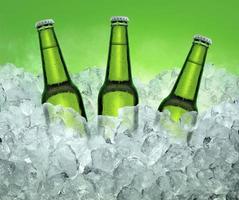 Three beer bottles getting cool in ice cubes. on the White color smoke background photo