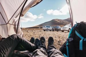 Legs of couple traveler relaxing inside a tent in wilderness on campground in summer photo