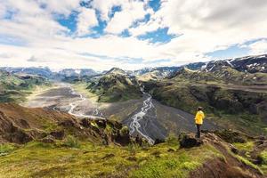 Valahnukur viewpoint with female hiker standing on peak and krossa river flowing through in icelandic highlands at Thorsmork, Iceland photo