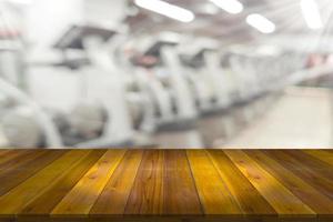 Empty wooden board space platform with blur fitness gym equipment background photo