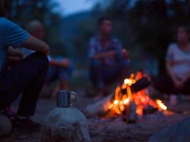 young friends relaxing around campfire photo