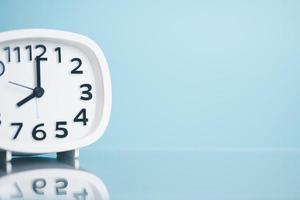 A white clock is placed on a wooden table, the concept of extinction of time, countdown, new beginning, appreciation of life, valuable use of time. photo