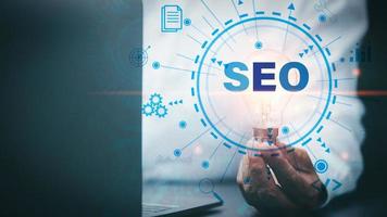 Marketer hold a light bulb showing SEO concepts, optimization analytics tools, search engine rankings, social media sites based on results analytics data. Customers use keywords to connect products photo