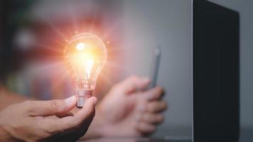 Businessman holding a light bulb showing ideas to brainstorm, imagine, inspire, innovative technology concepts through thinking, education, creativity. photo