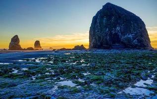 resplandor dorado detrás de pajar rock en cannon beach, oregon. foto