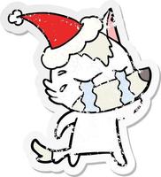 distressed sticker cartoon of a crying wolf wearing santa hat vector