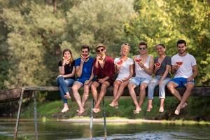 friends enjoying watermelon while sitting on the wooden bridge photo