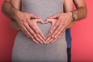 pregnant  couple showing heart with their hands photo