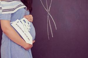 Portrait of pregnant woman in front of black chalkboard photo