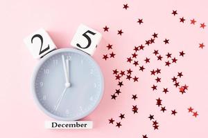 Christmas background with alarm clock and stars confetti on pink background photo