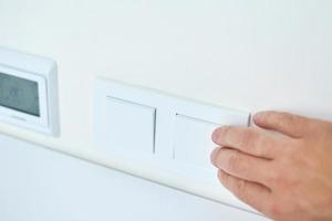 Hand is turning on or off on light switch, closeup photo