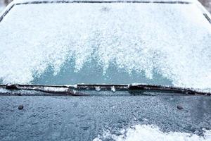 Close up of car windshield and wipers covered with ice and snow on winter day photo