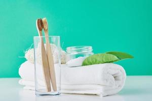Wooden bamboo toothbrushes in glass, baking soda and towel on a green background photo