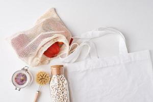 Glass jar, wooden brush and shopping bag with fresh vegetables photo