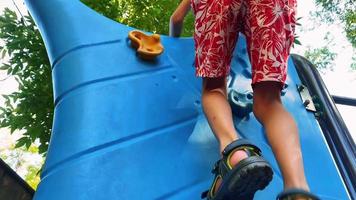 der junge spielt auf dem spielplatz, klettert auf einen plastikberg video