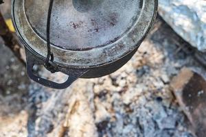 Close up of boiling pot at rhe campfire on picnic. Hike cooking concept photo