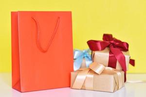 Gift box with ribbon and paper shopping bag on a yellow background photo