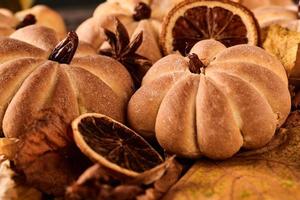 Homemade cookies in shape of pumpkin in autumn leaves. Halloween handmade cookies on a table, close up photo