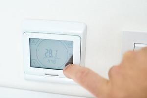 Men hand setting temperature on the underfloor heating control panel photo