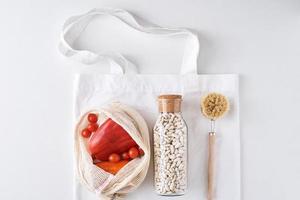 Fresh vegetables, beans in a glass bottle and textile shopping bag photo