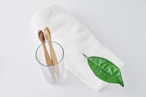 Two wooden bamboo eco friendly toothbrushes in glass and towel photo