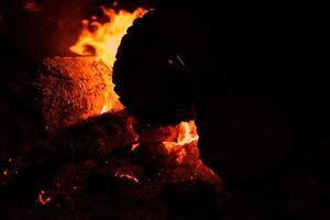 hoguera con chispas en la noche. calor de la quema de troncos y carbones en la oscuridad foto