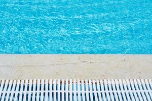 Background of water in blue swimming pool, water surface with a sun reflection photo