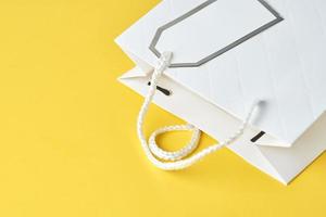 White shopping bag on yellow background, top view photo