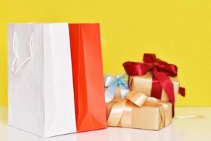 Gift box with ribbon and paper shopping bag on a yellow background photo