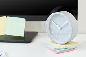 lugar de trabajo con reloj, suministros de oficina y notas adhesivas foto