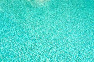 fondo de agua en la piscina azul, superficie de agua con un reflejo del sol foto