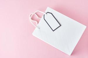 White shopping bag on pink background, top view photo