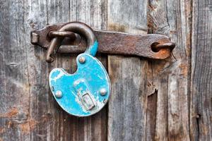 Blue old rusty unlocked padlock on wooden door photo