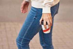 Woman hand with paper cup of coffee take away in a city street photo