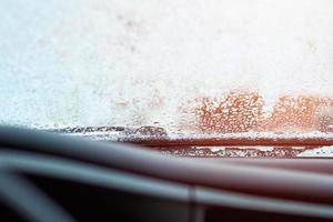 Close up of car windshield and wipers covered with ice and snow on winter day photo