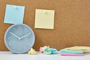 Sticky notes on a cork board and alarm clock in workplace office or home photo